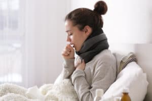 Jovem mulher doente na cama em casa ilustrando um dos sintomas da gripe H3N2